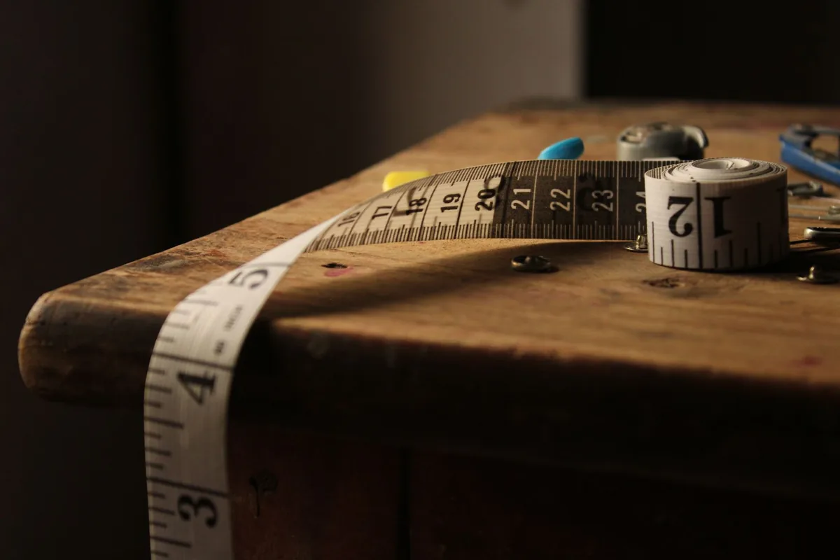 A cloth tape measure unrolled across the edge of an old wooden table in warm light