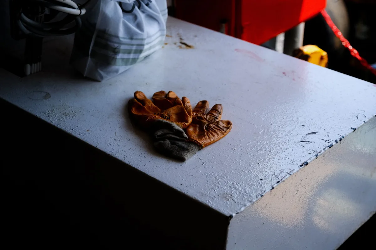 A pair of worn tan leather work gloves lying on a white painted workbench