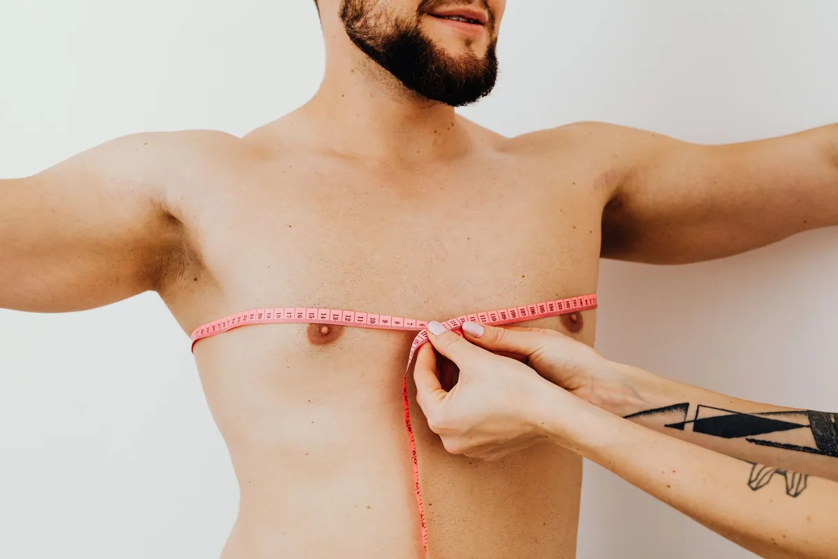 A man having his chest measured with a pink tape measure
