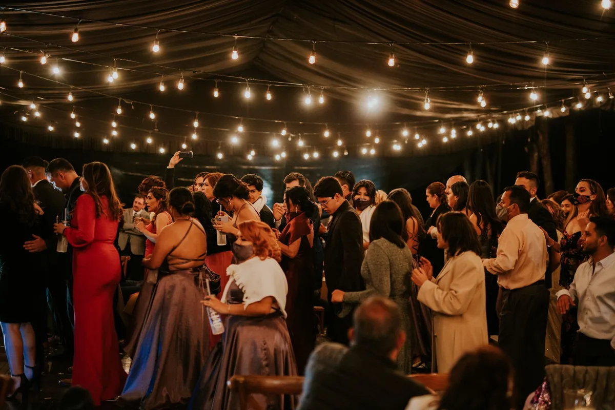 Guests dancing under string lights at an evening reception