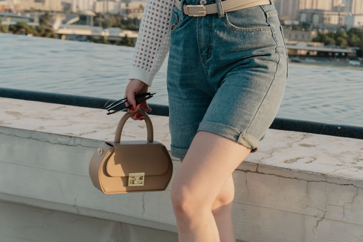 A woman in denim shorts holding a bag on a city rooftop