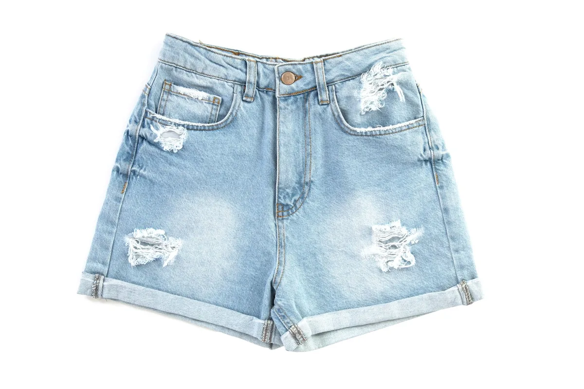 A pair of distressed denim shorts on a white background