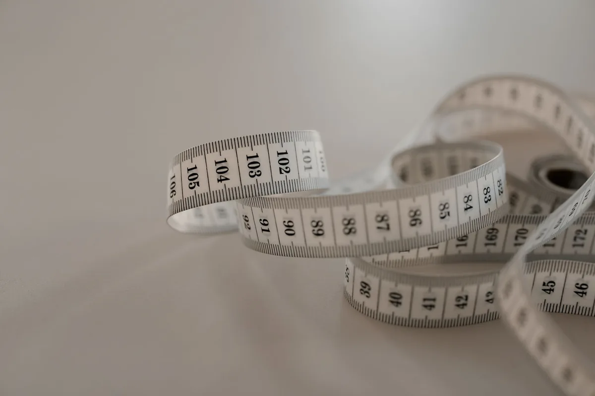 A white tape measure in loose coils on a grey surface