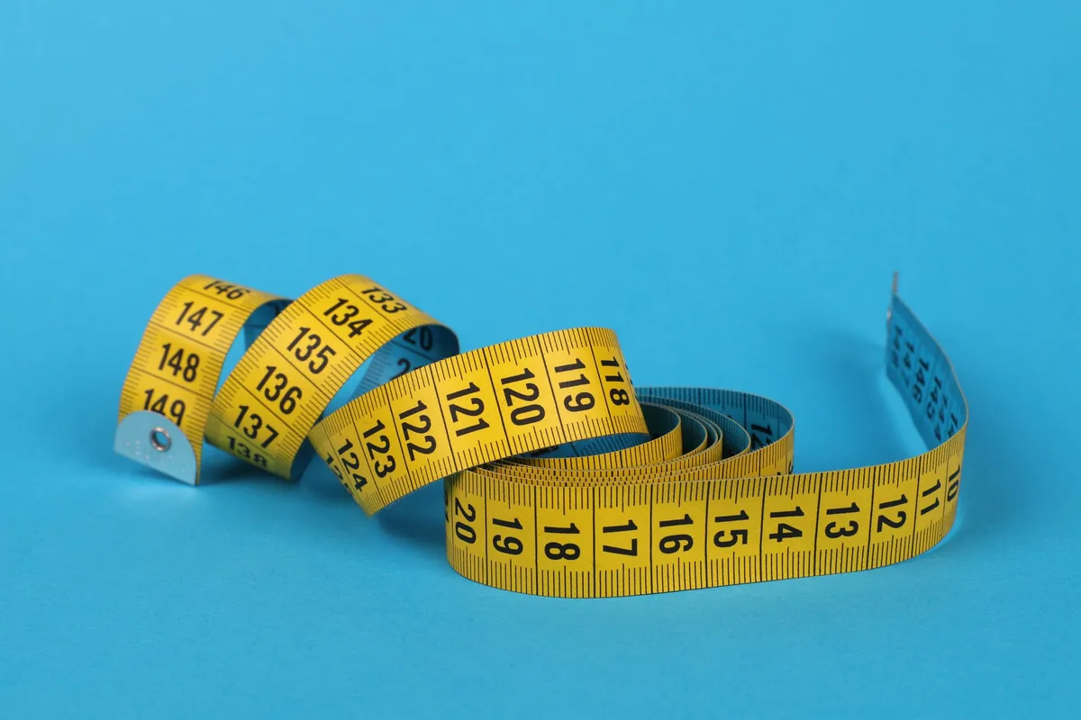 A yellow tape measure coiled on a blue background