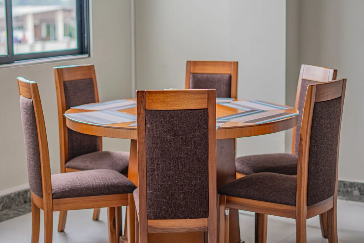 Wooden dining chairs with brown fabric seats and backs around a round table with striped placemats